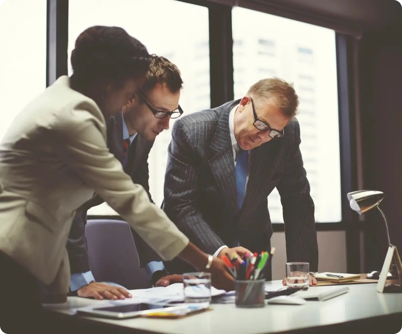 Three men in suits and ties working on a project.